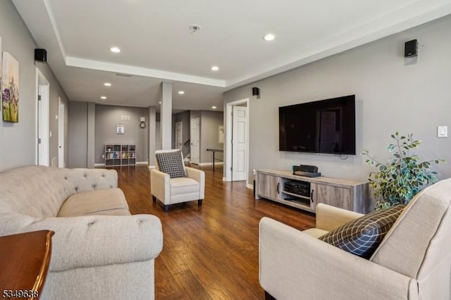 living area with recessed lighting, a raised ceiling, and wood finished floors