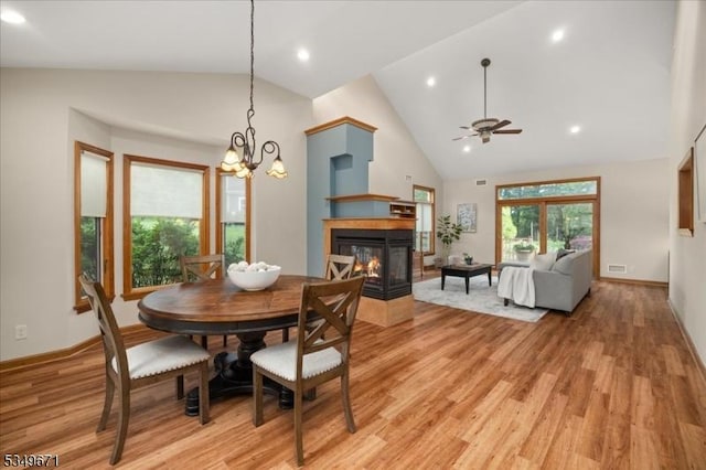 dining area featuring a ceiling fan, light wood-type flooring, a multi sided fireplace, high vaulted ceiling, and recessed lighting