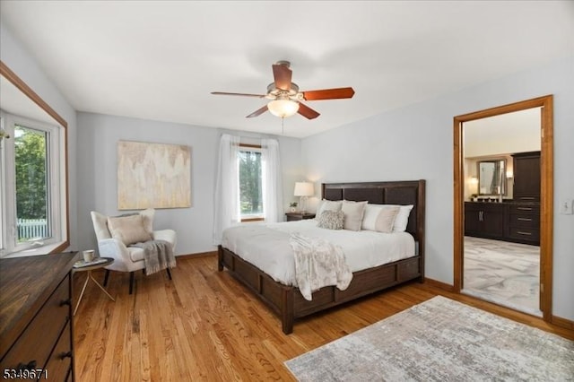 bedroom with multiple windows, light wood-type flooring, and baseboards