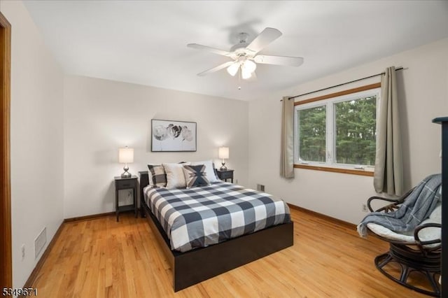 bedroom featuring baseboards, light wood finished floors, and a ceiling fan
