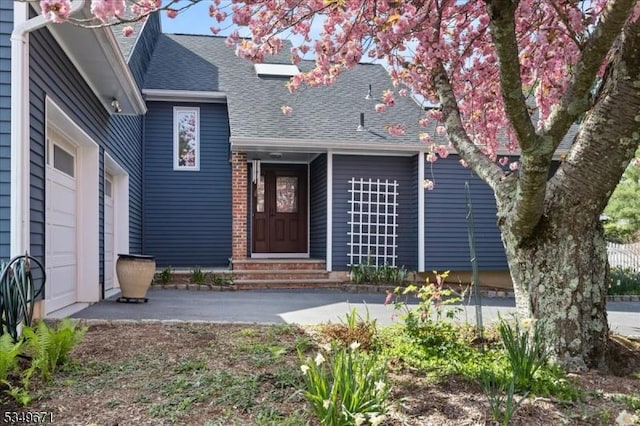 view of front of home with a shingled roof, entry steps, and a garage