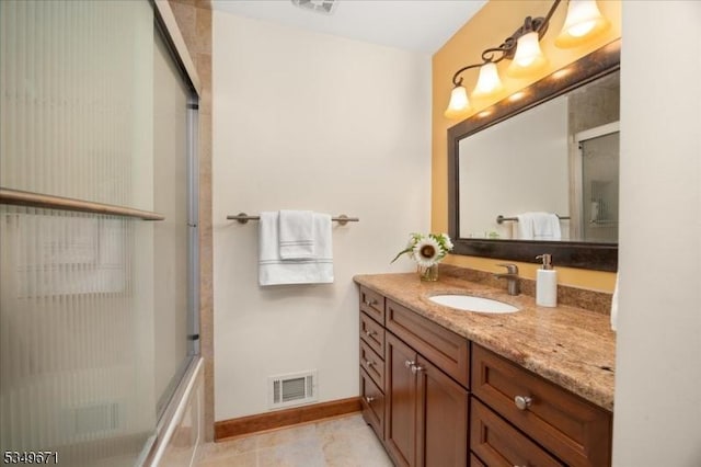 full bath with vanity, baseboards, and shower / bath combination with glass door