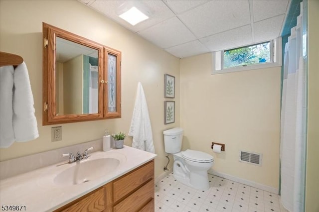 full bathroom featuring tile patterned floors, a paneled ceiling, toilet, vanity, and baseboards
