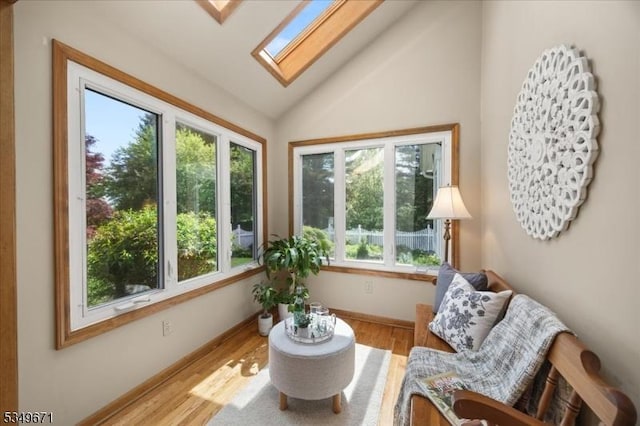 sunroom / solarium with a skylight, lofted ceiling, wood finished floors, and baseboards