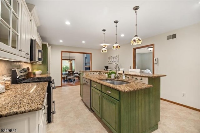 kitchen featuring green cabinetry, stainless steel appliances, a sink, white cabinets, and tasteful backsplash