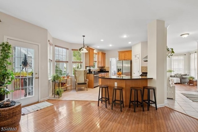 kitchen featuring light wood-style floors, plenty of natural light, appliances with stainless steel finishes, and dark countertops