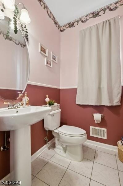 bathroom featuring toilet, baseboards, visible vents, and tile patterned floors