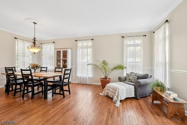 dining room featuring crown molding, baseboards, and hardwood / wood-style flooring