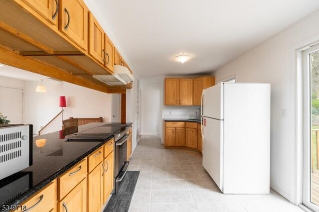 kitchen featuring under cabinet range hood, light tile patterned floors, a sink, freestanding refrigerator, and electric range