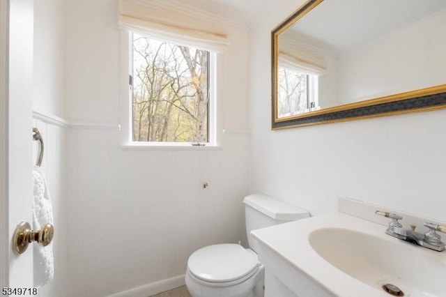 bathroom with toilet, vanity, and a wainscoted wall