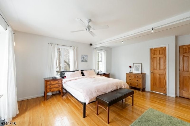 bedroom with rail lighting, baseboards, a ceiling fan, and light wood-style flooring