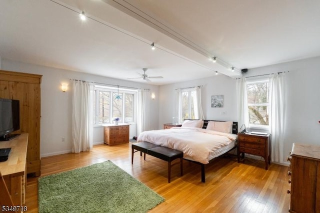 bedroom with light wood finished floors, baseboards, and multiple windows