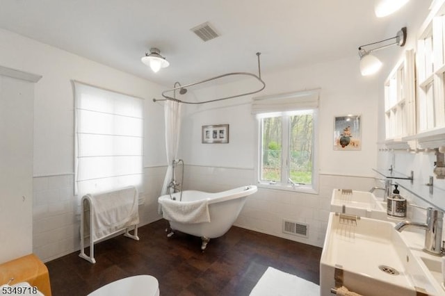 bathroom featuring tile walls, wainscoting, and visible vents