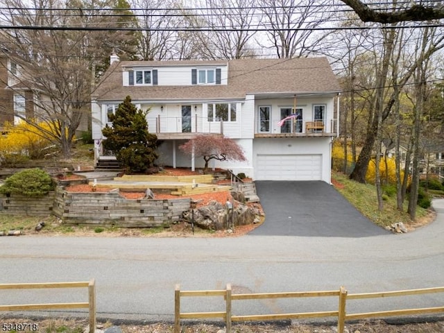 view of front of property with an attached garage, driveway, fence, and a balcony