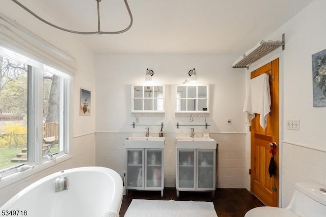 full bathroom featuring wainscoting, toilet, a soaking tub, and tile walls