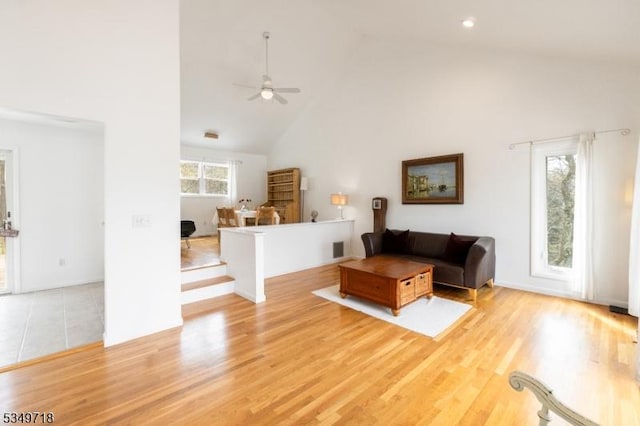 living area with a ceiling fan, wood finished floors, and high vaulted ceiling