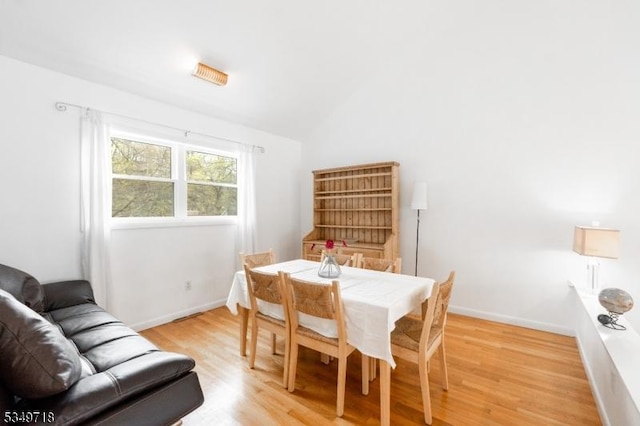 dining room featuring vaulted ceiling, baseboards, and light wood-style floors