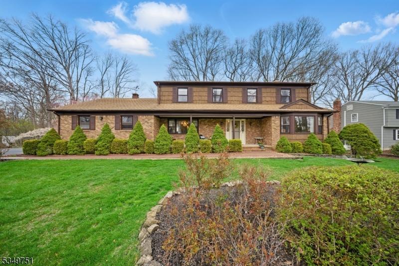 traditional-style house with brick siding, a front lawn, and a chimney