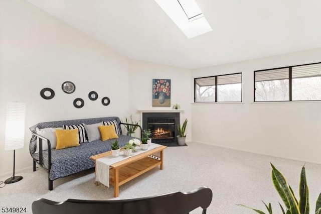 carpeted living room with baseboards, a fireplace with flush hearth, and vaulted ceiling with skylight