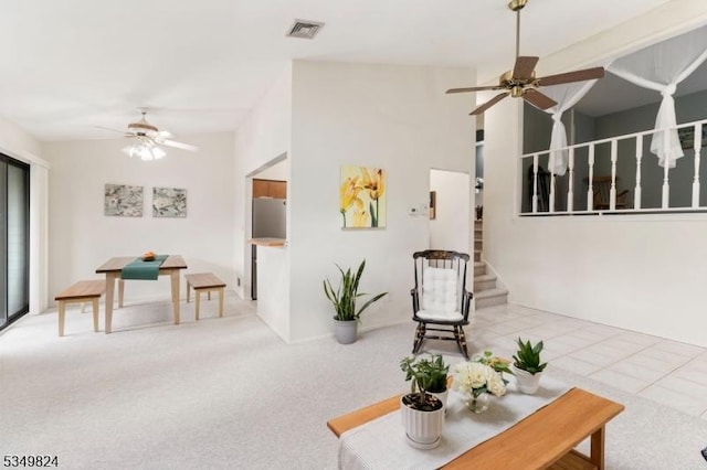 living area with visible vents, a ceiling fan, carpet, and stairway