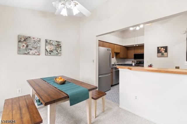kitchen with ceiling fan, light colored carpet, appliances with stainless steel finishes, a sink, and a peninsula