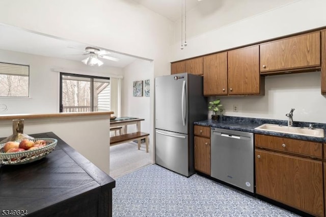 kitchen with ceiling fan, dark countertops, a sink, brown cabinetry, and stainless steel appliances