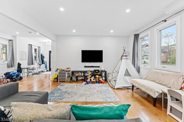 living room featuring light wood finished floors, recessed lighting, and a healthy amount of sunlight