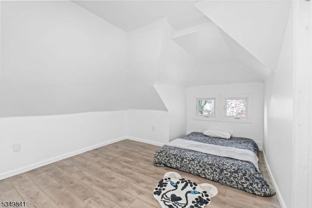 bedroom with wood finished floors, baseboards, and lofted ceiling