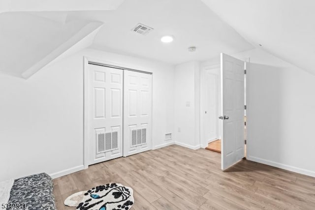 additional living space with visible vents, baseboards, vaulted ceiling, and wood finished floors