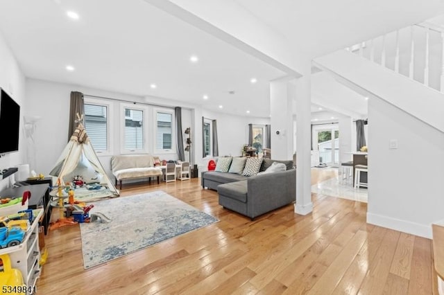 living room featuring light wood-type flooring, baseboards, stairway, and recessed lighting