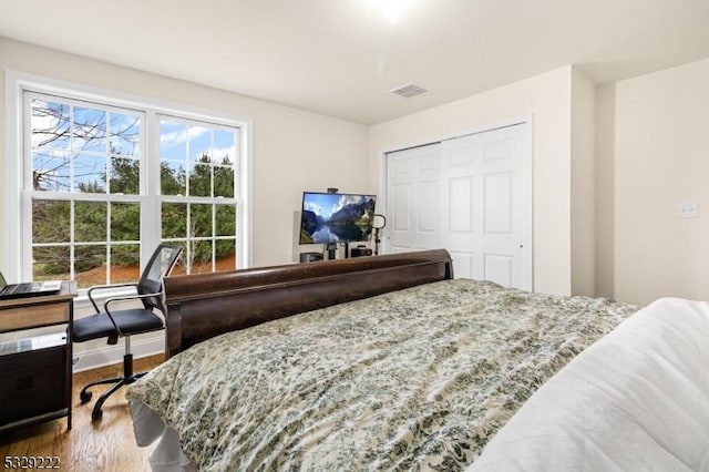 bedroom featuring visible vents, a closet, and wood finished floors