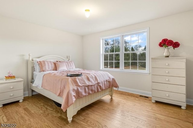 bedroom with light wood-style floors, baseboards, and visible vents