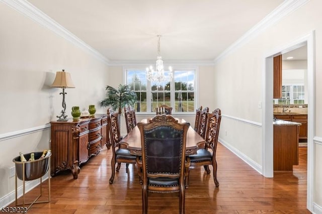 dining space with hardwood / wood-style floors, an inviting chandelier, crown molding, and baseboards