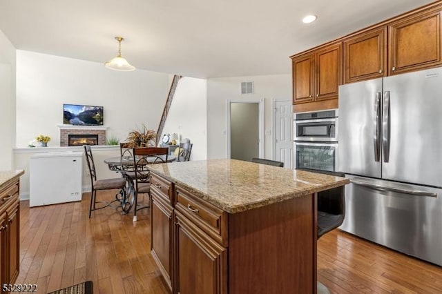 kitchen featuring dark wood-type flooring, a fireplace, visible vents, and stainless steel appliances