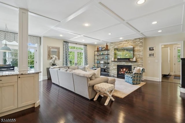 living area with coffered ceiling, baseboards, dark wood-style floors, and a stone fireplace