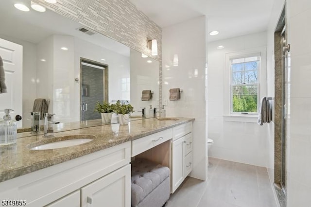 bathroom featuring a sink, visible vents, double vanity, and a stall shower