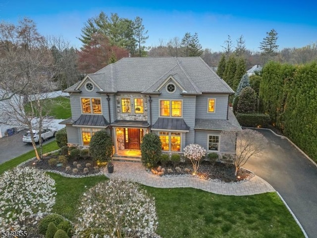 view of front facade with driveway, a standing seam roof, a front lawn, and metal roof