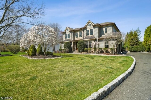 view of front of home with aphalt driveway, a garage, and a front lawn