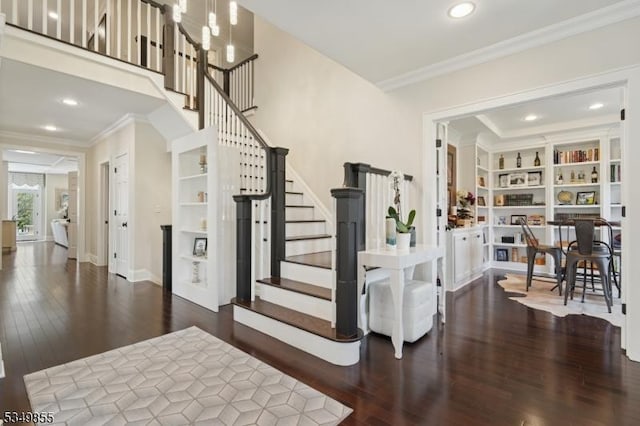 stairway with crown molding, built in shelves, and wood finished floors