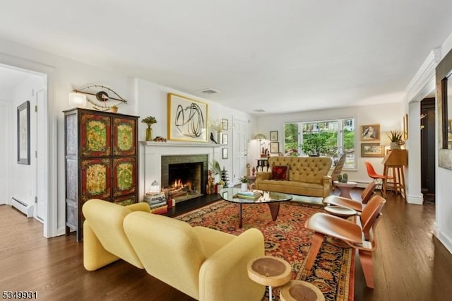 living room featuring a brick fireplace, a baseboard heating unit, visible vents, and dark wood-type flooring