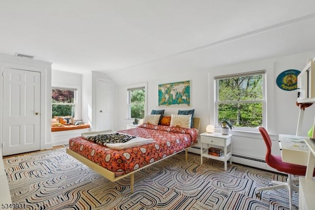 bedroom featuring visible vents, a baseboard heating unit, lofted ceiling, and multiple windows