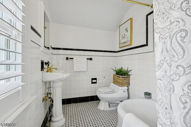 full bath featuring toilet, tile walls, and a wainscoted wall