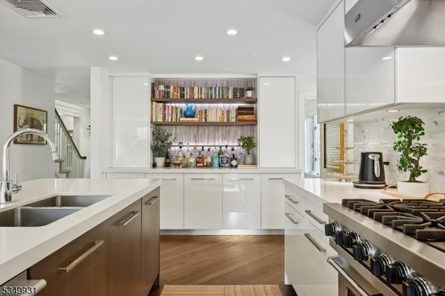 bar featuring visible vents, wood finished floors, a sink, under cabinet range hood, and recessed lighting