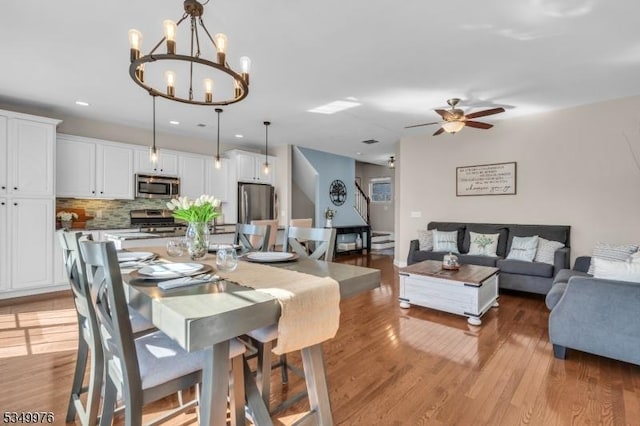 dining room featuring light wood-type flooring, ceiling fan with notable chandelier, and recessed lighting