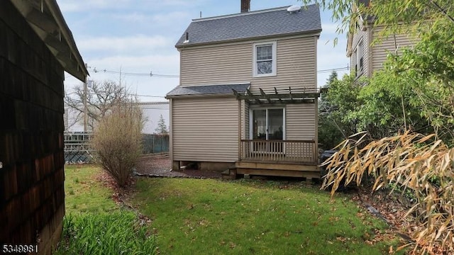 back of house with a pergola, a yard, fence, a wooden deck, and roof with shingles