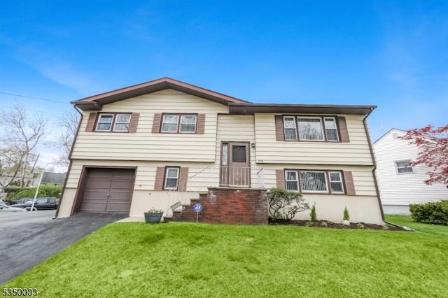 raised ranch with an attached garage, a front yard, and asphalt driveway