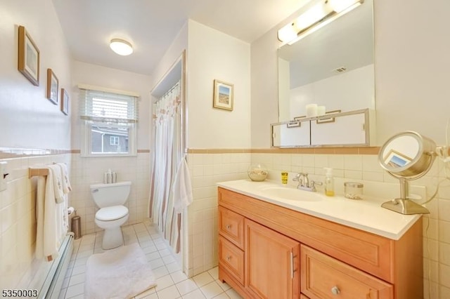 bathroom with tile walls, toilet, tile patterned floors, wainscoting, and vanity