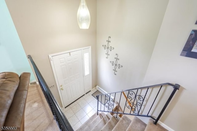 foyer featuring baseboards, tile patterned flooring, and a high ceiling