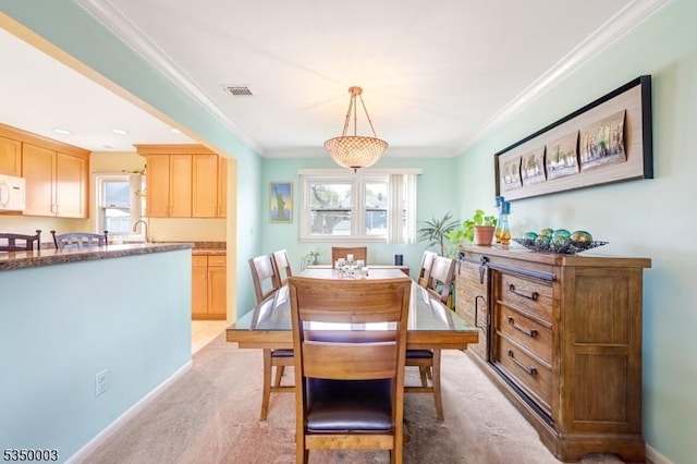 dining room with ornamental molding, light colored carpet, and baseboards