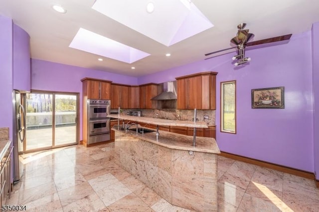 155 Route560, Sandyston Twp, NJ 07851 - kitchen featuring wall chimney exhaust hood, stainless steel appliances, a skylight, brown cabinets, and recessed lighting